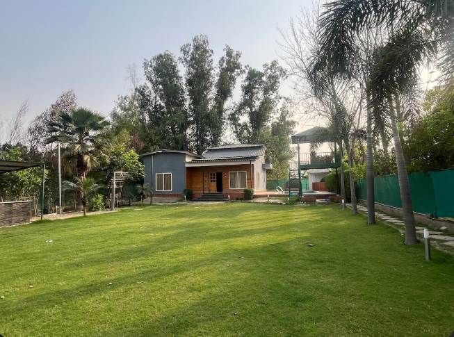 Expostay Farm Sector 151 Noida with spacious green lawn and farmhouse exterior